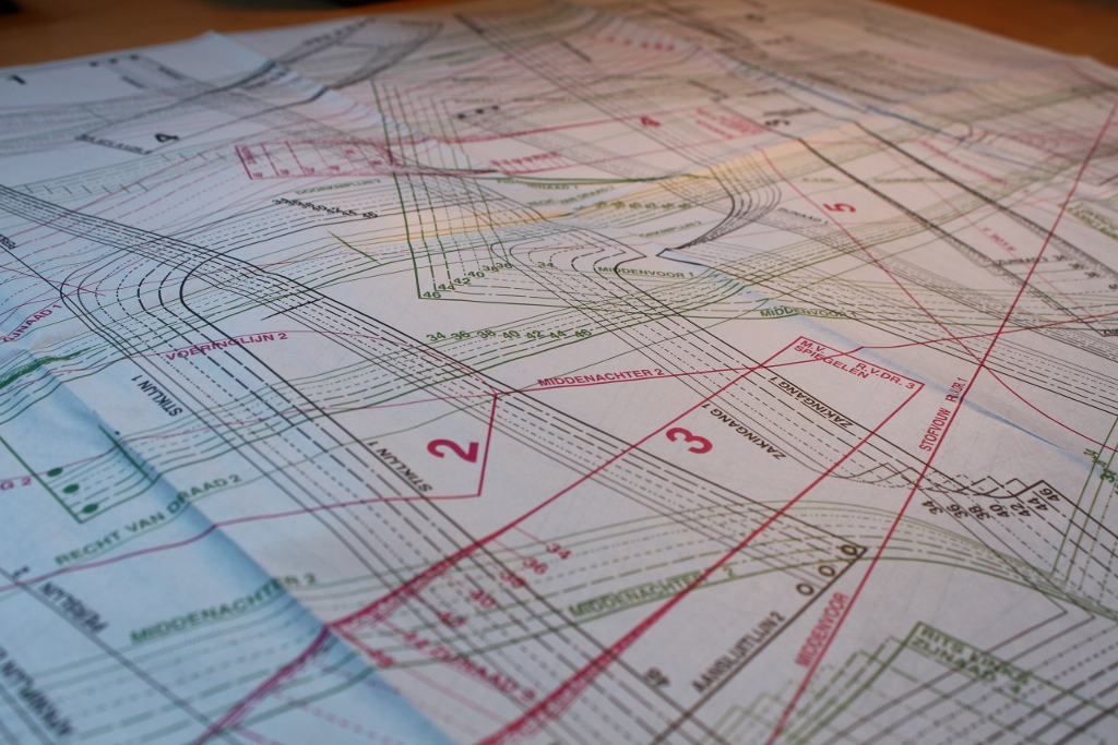 De werktafel in het atelier met stof, patroon en gereedschap.